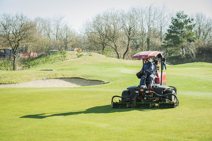 Greenkeeper vacature, greenkeeper aan het maaien